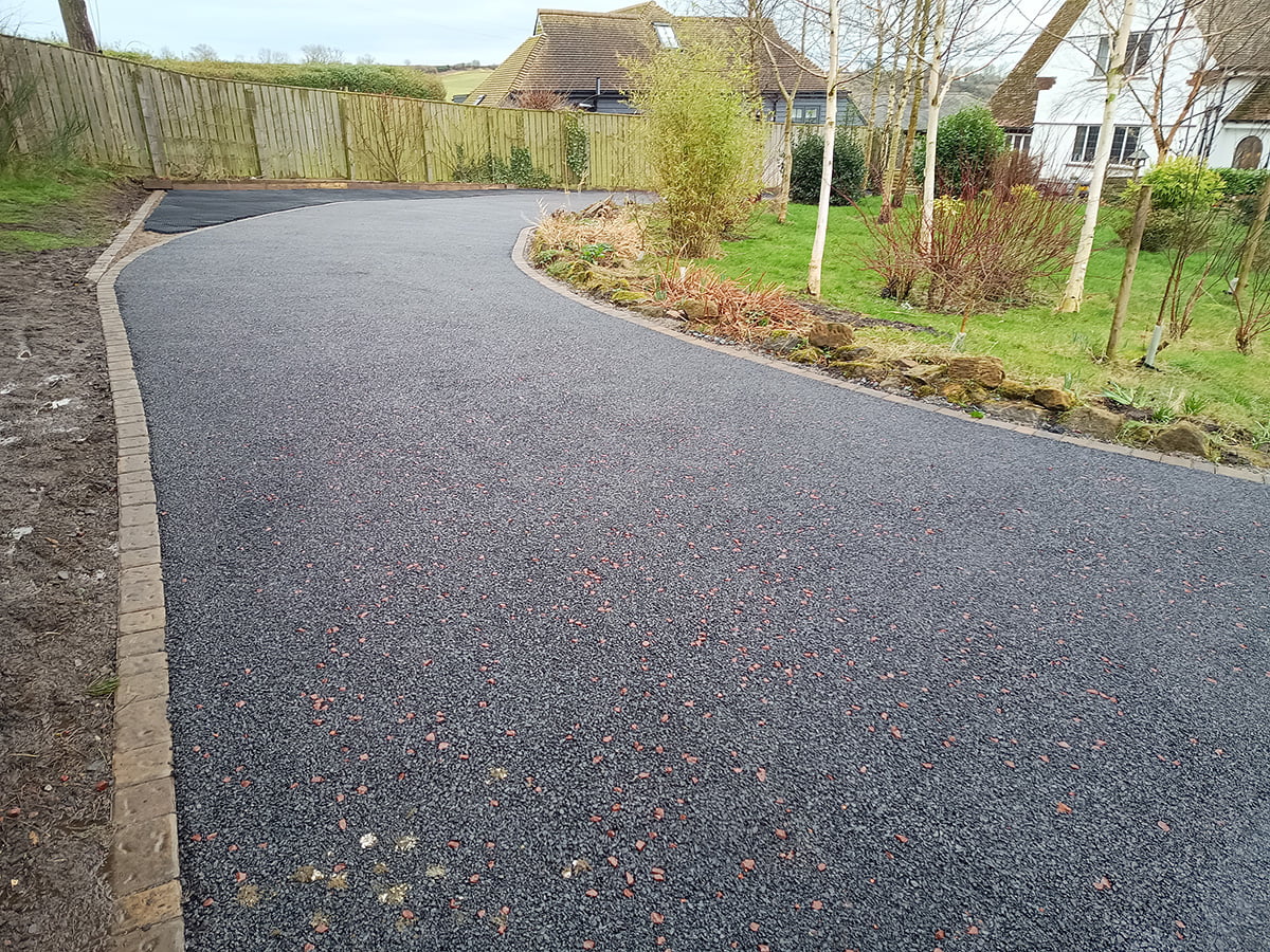 Rustic block paved border surrounding a tarmac driveway in Lesbury, Northumberland NE61, creating a charming contrast and defining the perimeter of the property.