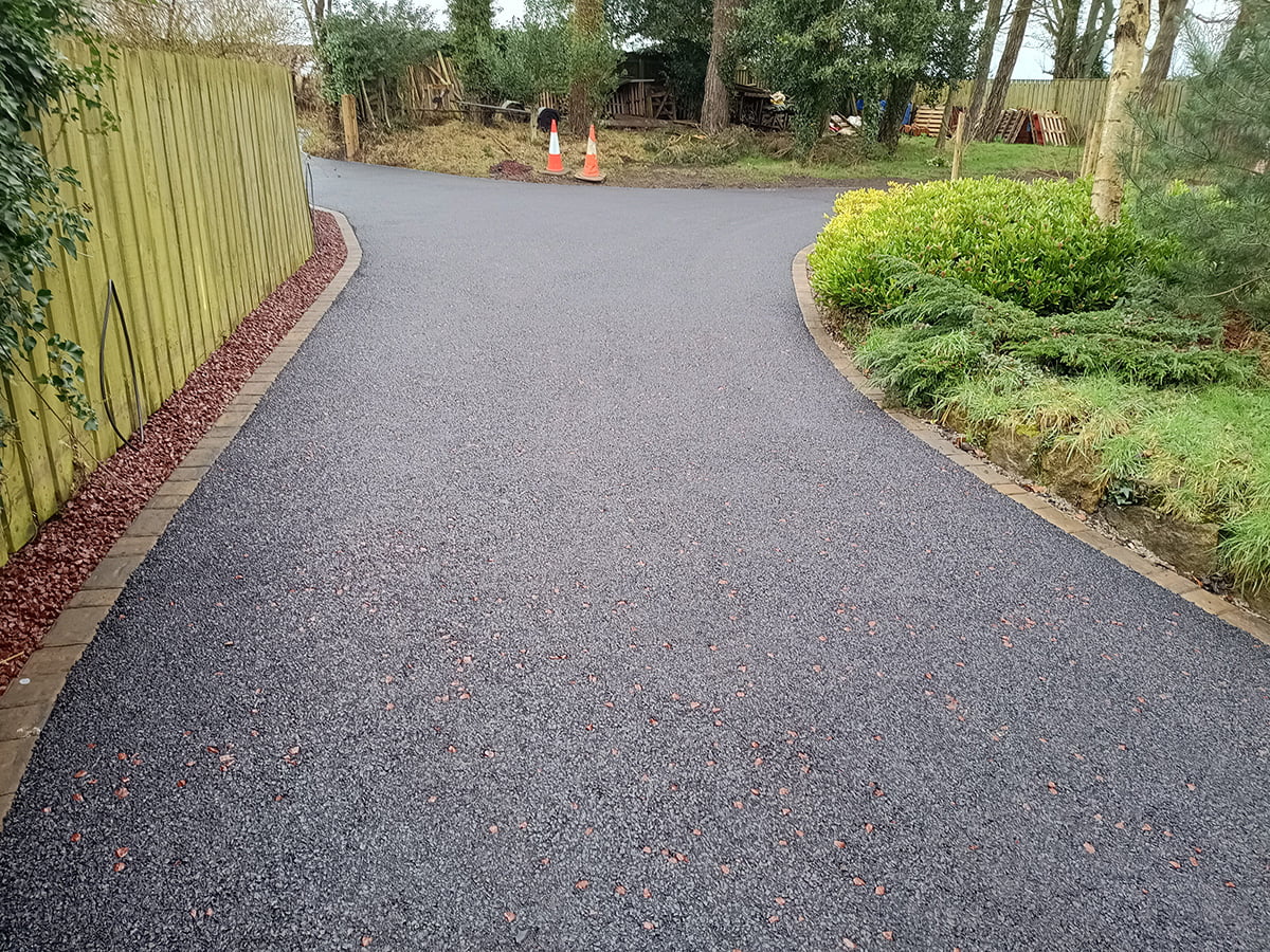 A tarmac driveway featuring a classic black surface with red pre coated chip accents, meticulously installed by W Miller & Sons in Lesbury, Alnwick