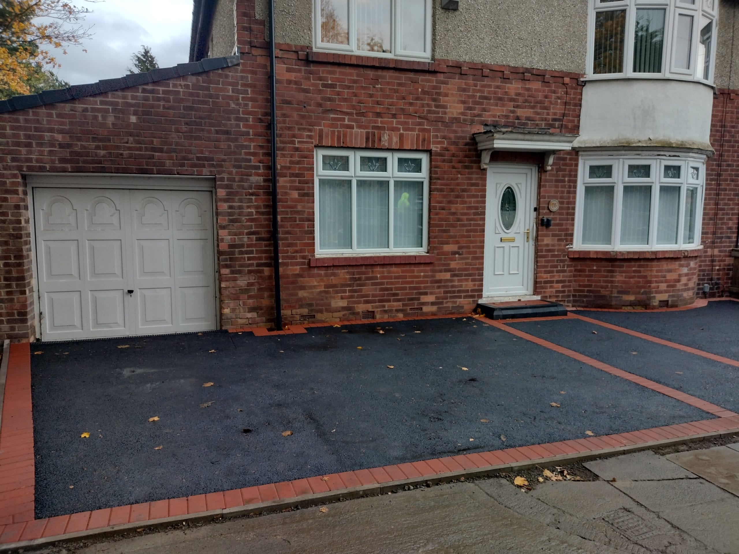 Tarmac driveway with a red brick border