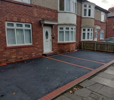 Tarmac driveway with a red brick border
